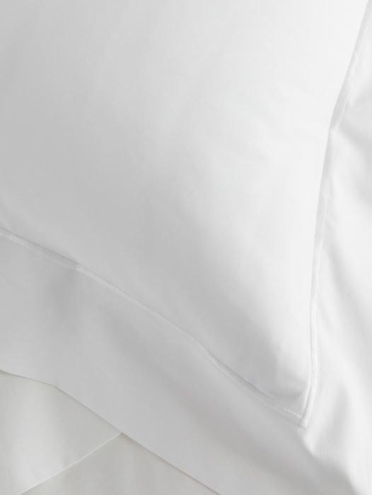 a close up of a white bed with pillows and sheets