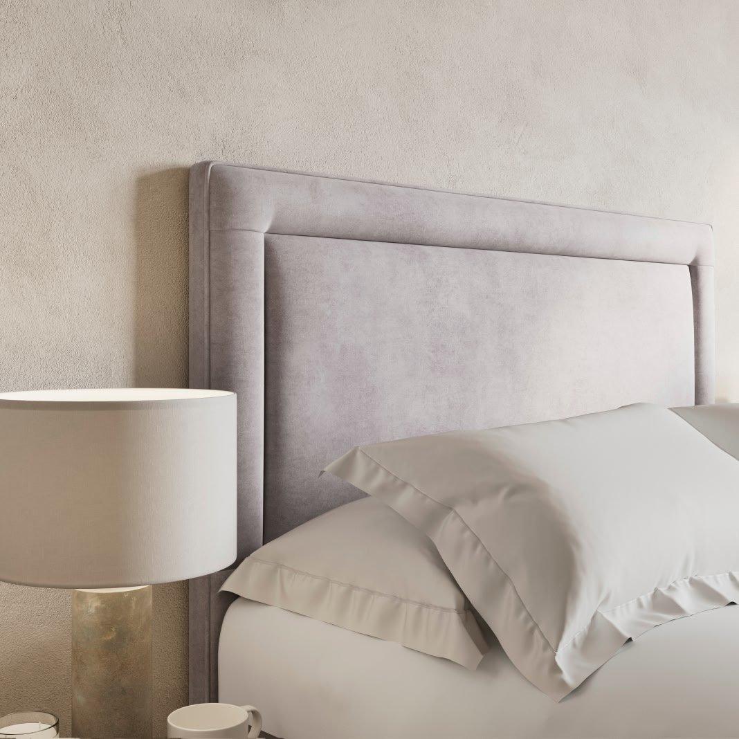 a bed with a white headboard and pillows on it