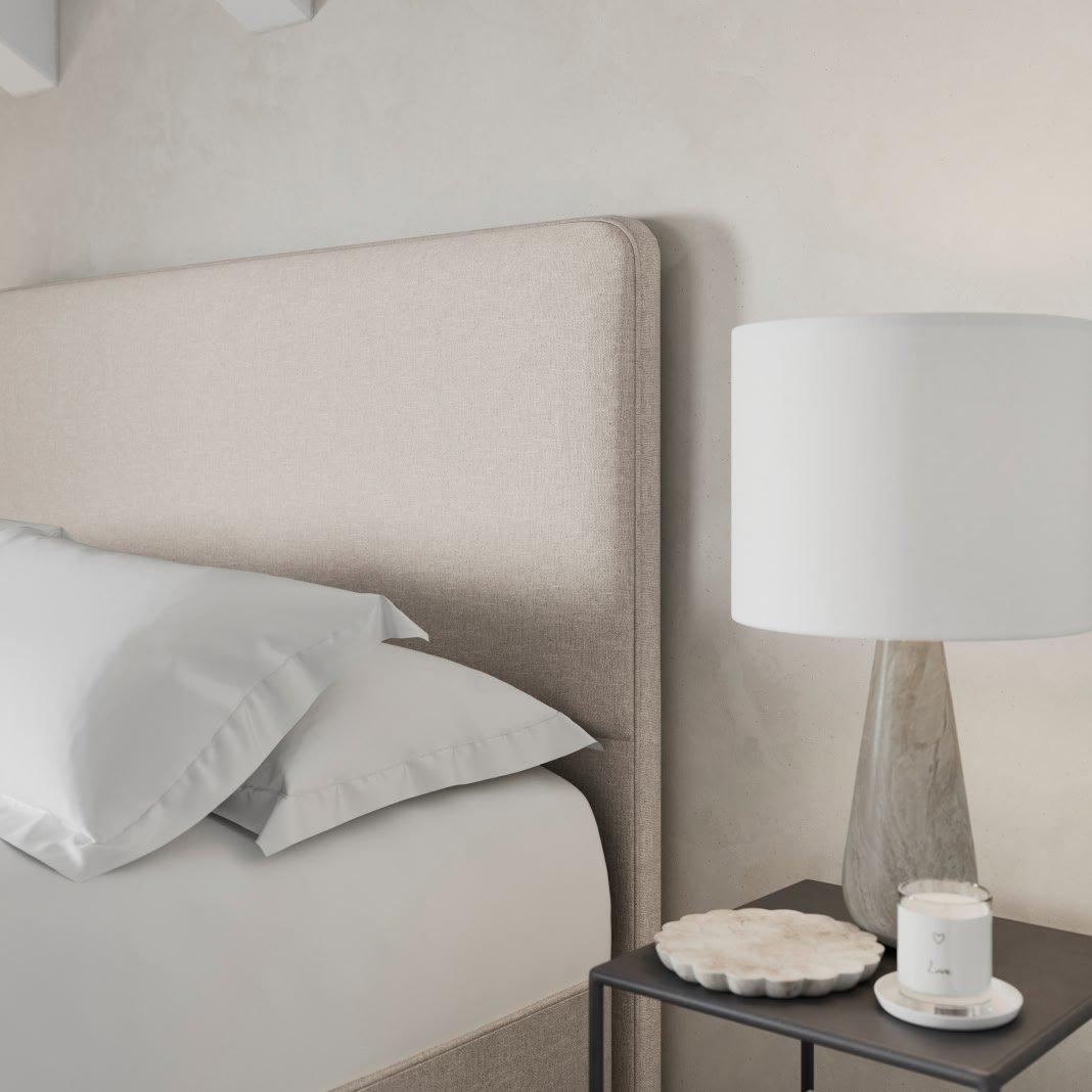 a bed with a white headboard and a nightstand with a lamp