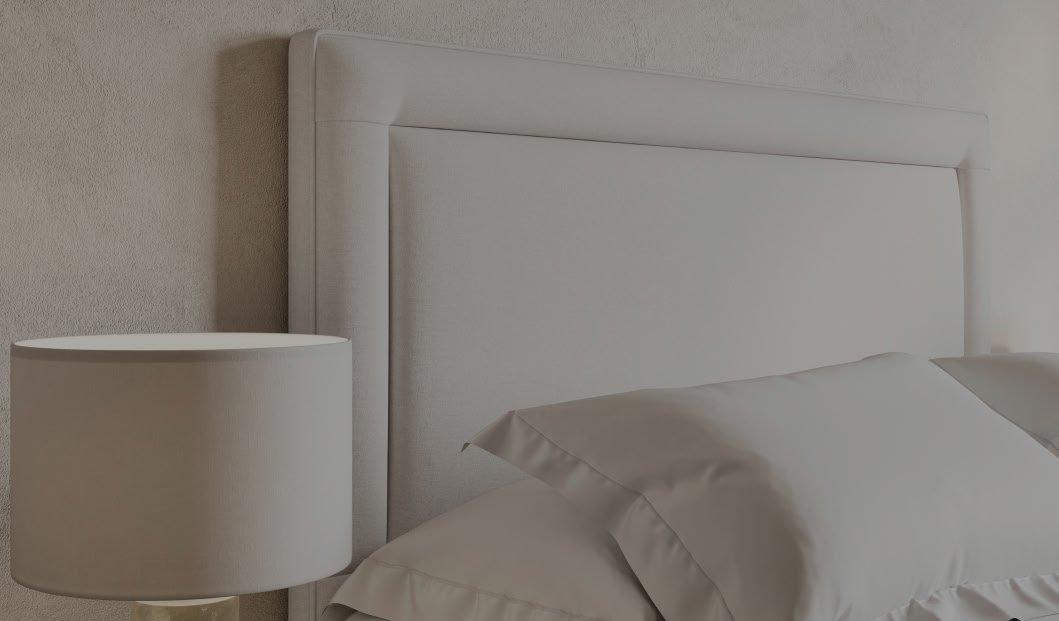 a bed with white sheets and pillows and a lamp on the night stand