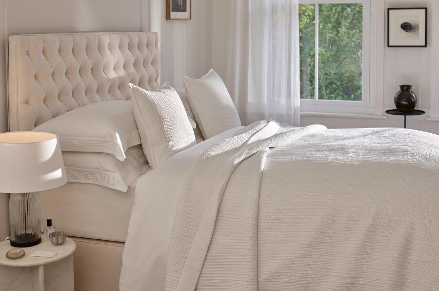 a bed with white sheets and pillows in a bedroom