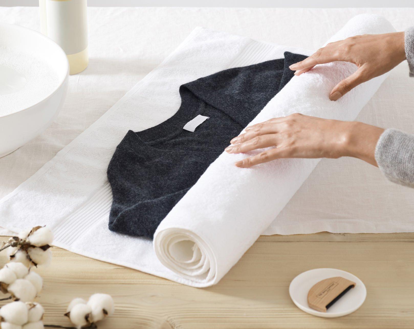 a person rolling a towel on a table with a cotton ball
