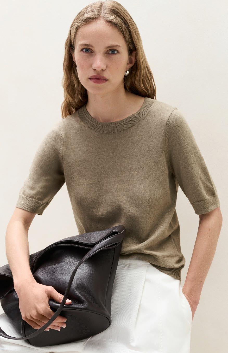 a woman sitting with a black purse on her lap