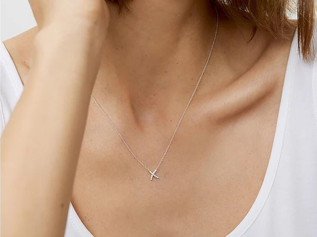 a woman wearing a necklace with a small cross on it