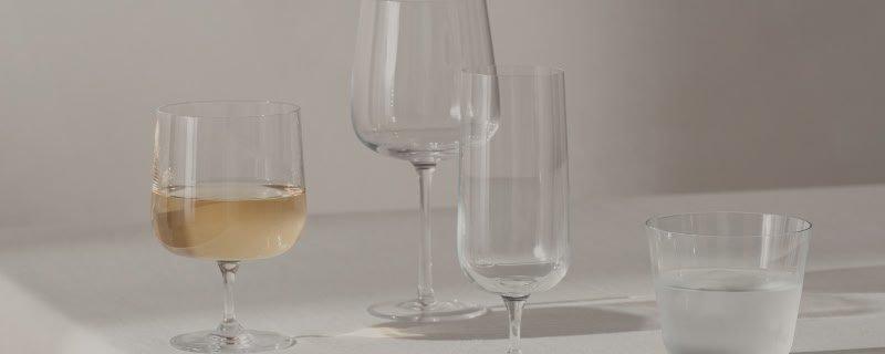 a close up of a white wall with wine glasses stood on a table
