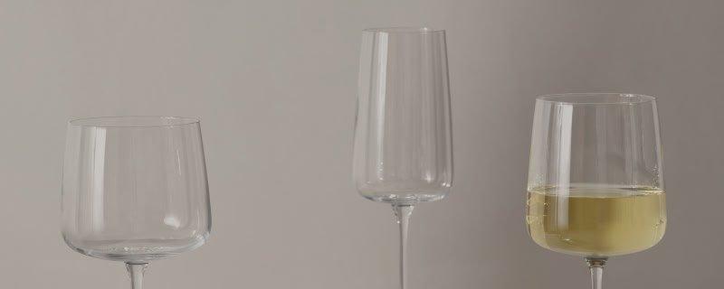 a close up of a white wall with wine glasses stood on a table