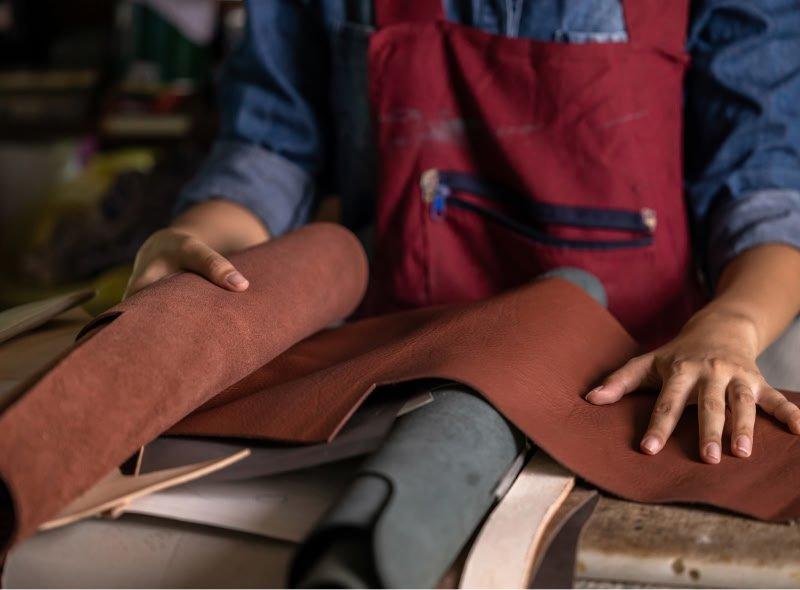 a person working with leather on a table in a factory