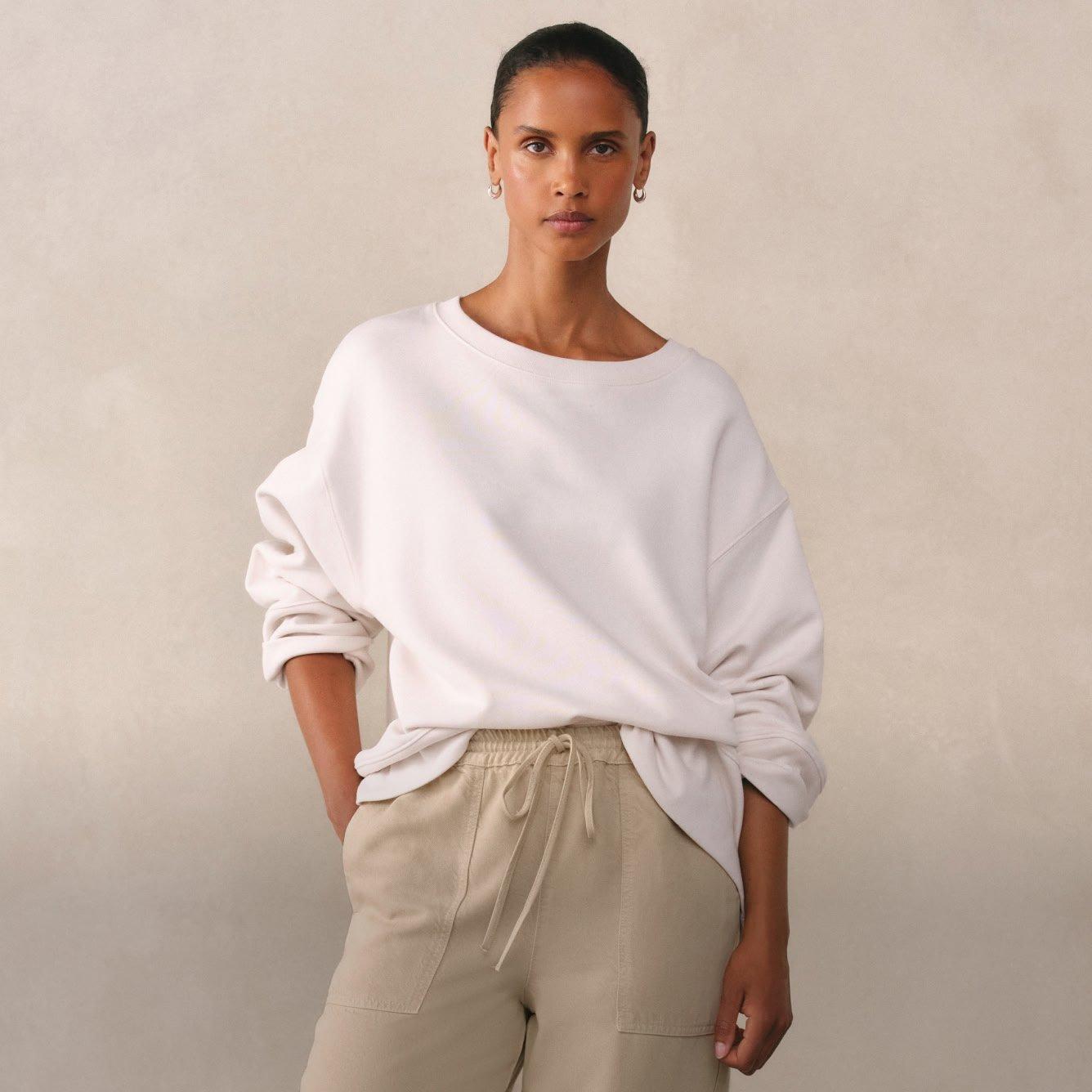 a woman in a white sweatshirt and beige pants