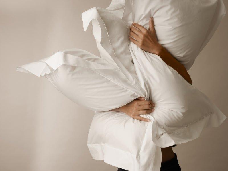 a woman is holding a pillow over her head and shoulders