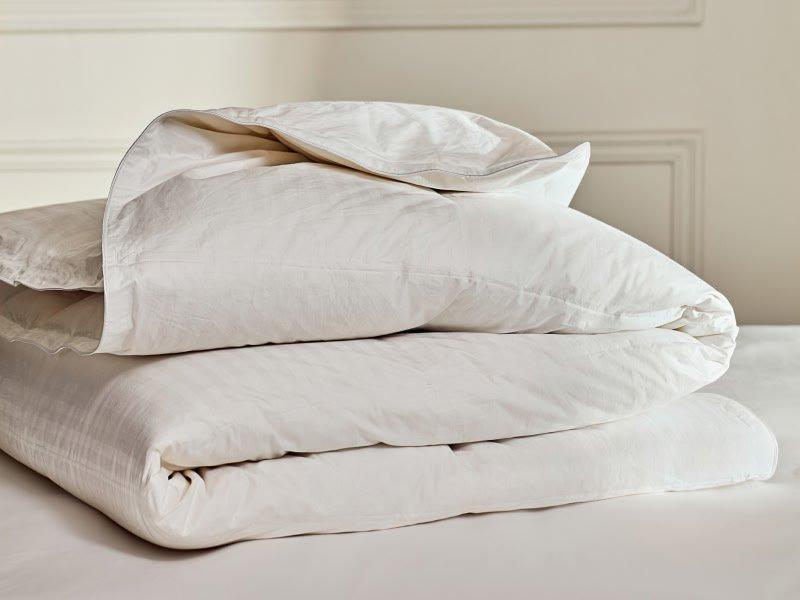 a stack of white pillows on top of a bed with a white sheet