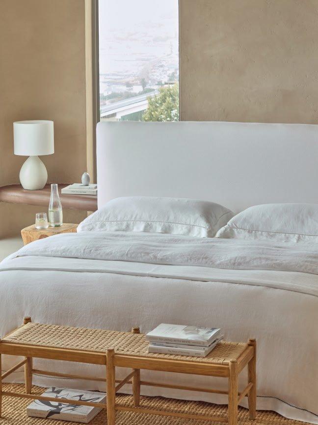 a bed with white sheets and pillows in a bedroom