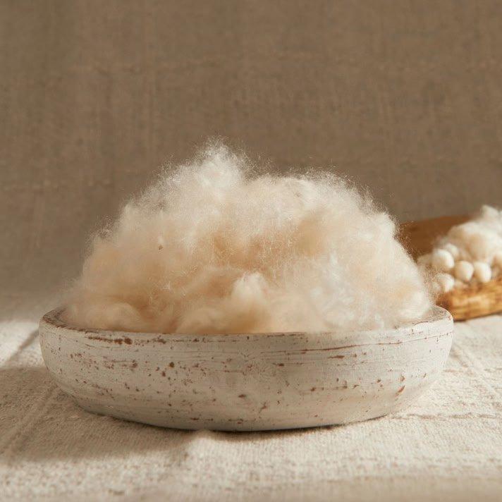 a bowl of cotton on a table next to a spoon