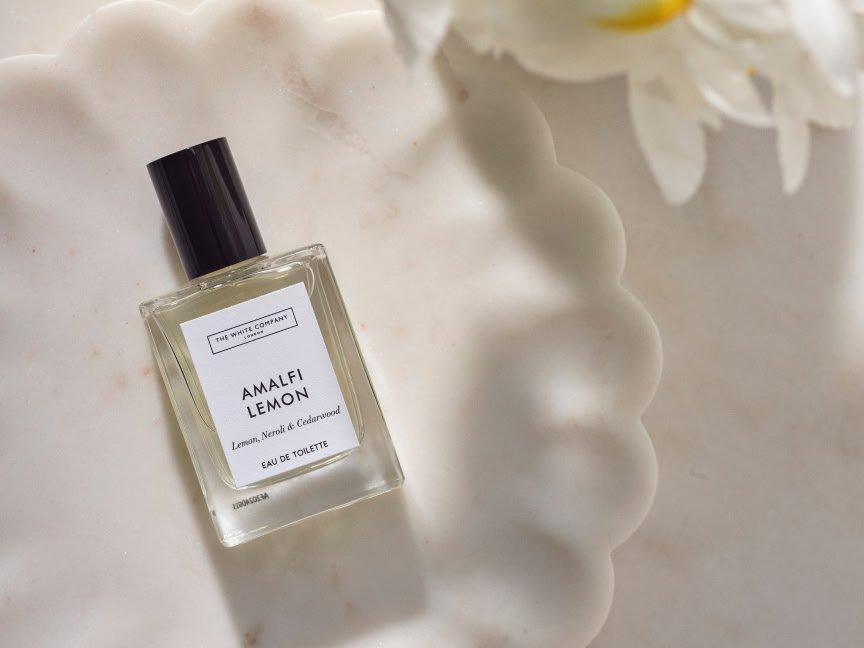 a bottle of amla lemon on a white plate next to a flower