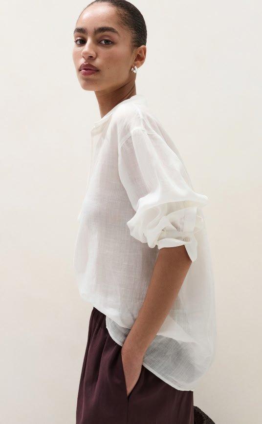 a woman in a white shirt and brown pants standing up