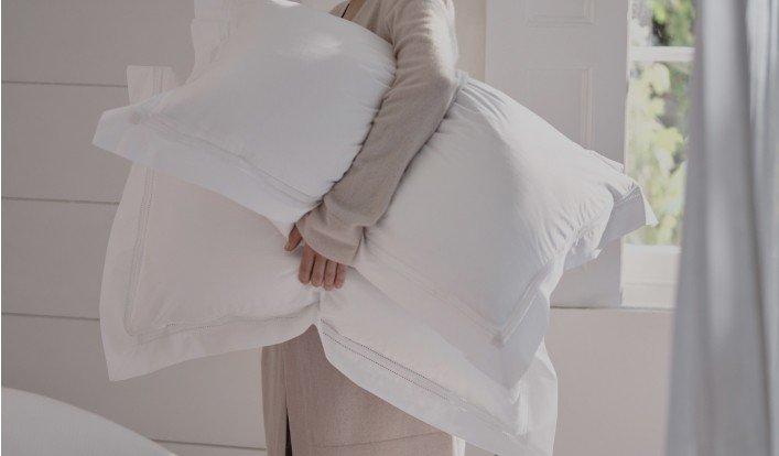 a woman holding a pillow in her hands while standing in a room