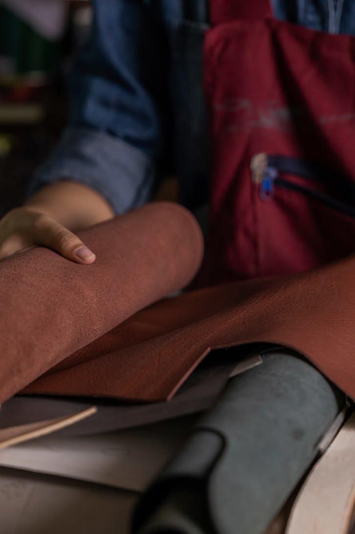 a person working on a piece of leather with a pair of scissors
