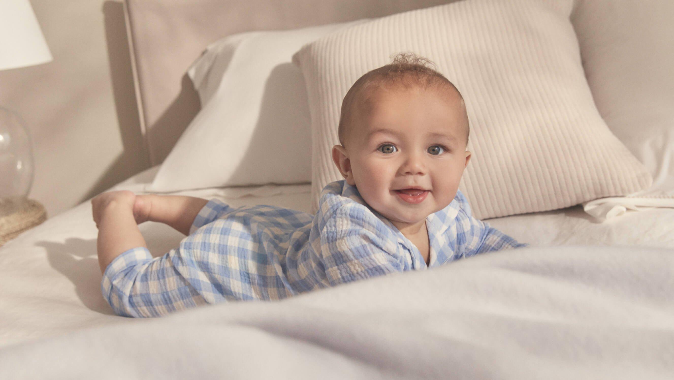 a baby laying on a bed with a white sheet