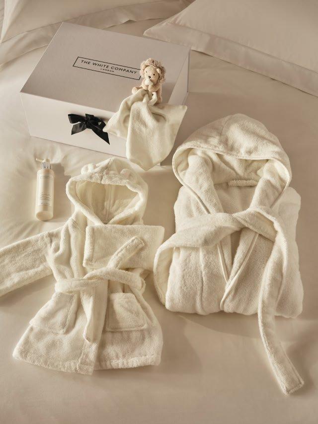 a white robe and a stuffed animal on a bed