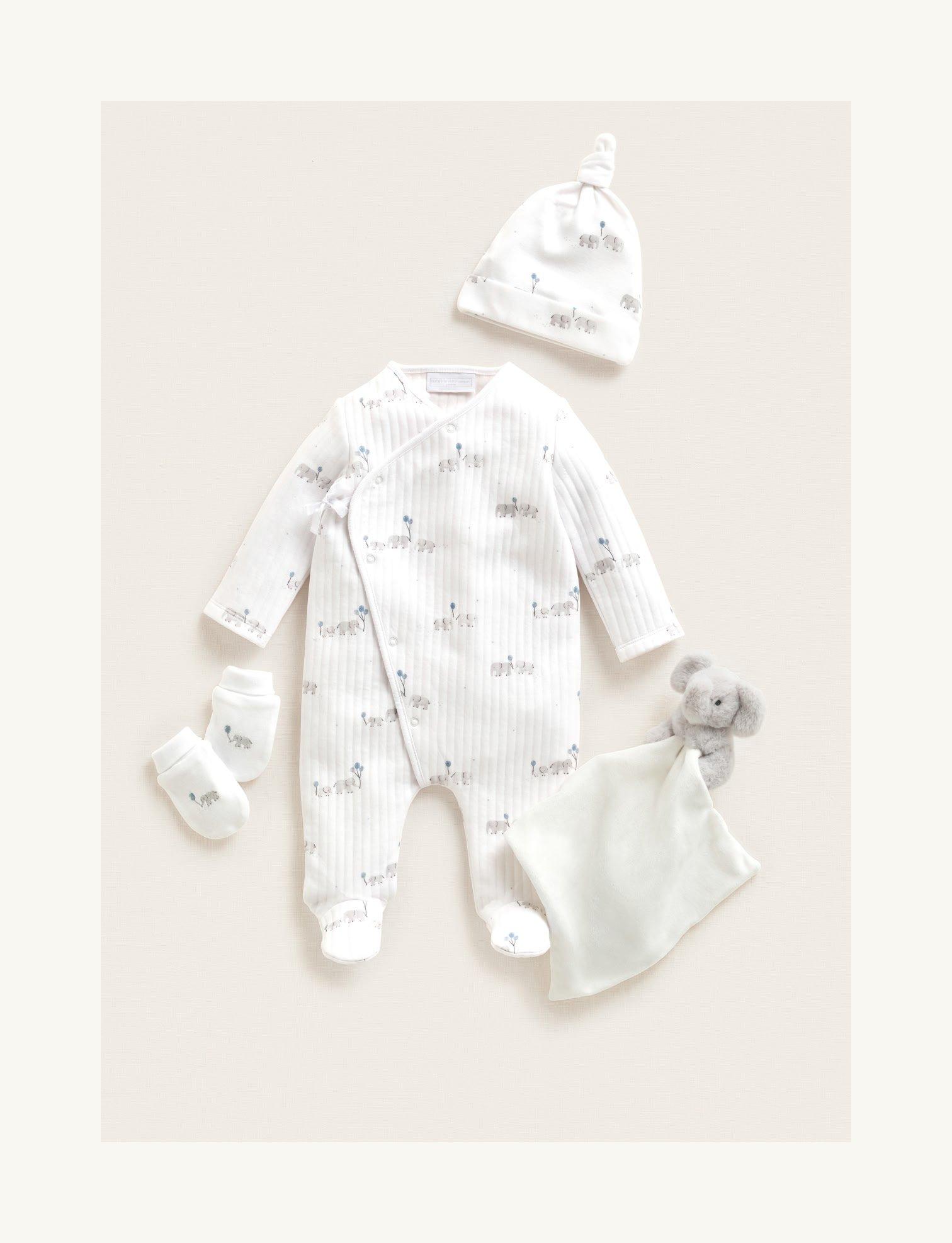 a baby's white outfit with a hat, mittens and a stuffed animal