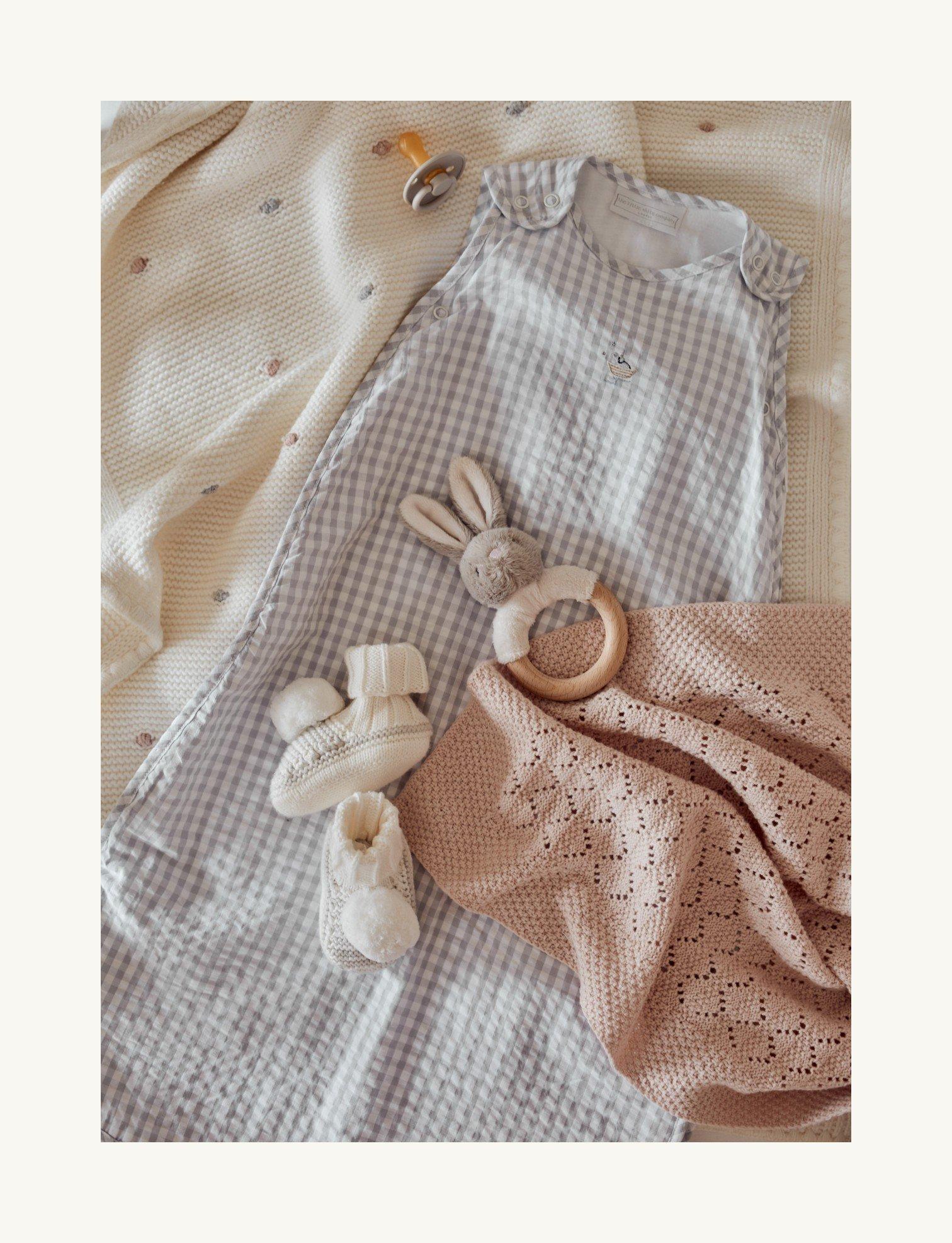 a baby's clothes laid out on a bed with a blanket