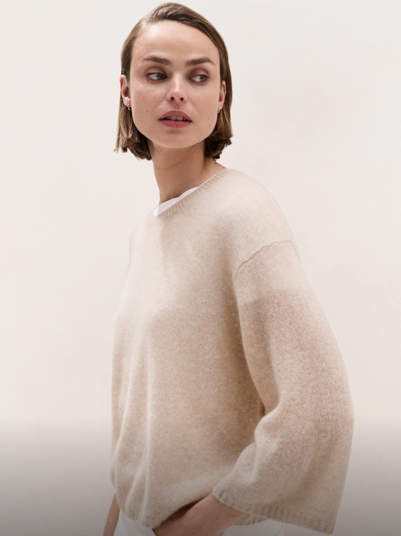 a woman in a white shirt and a beige sweater