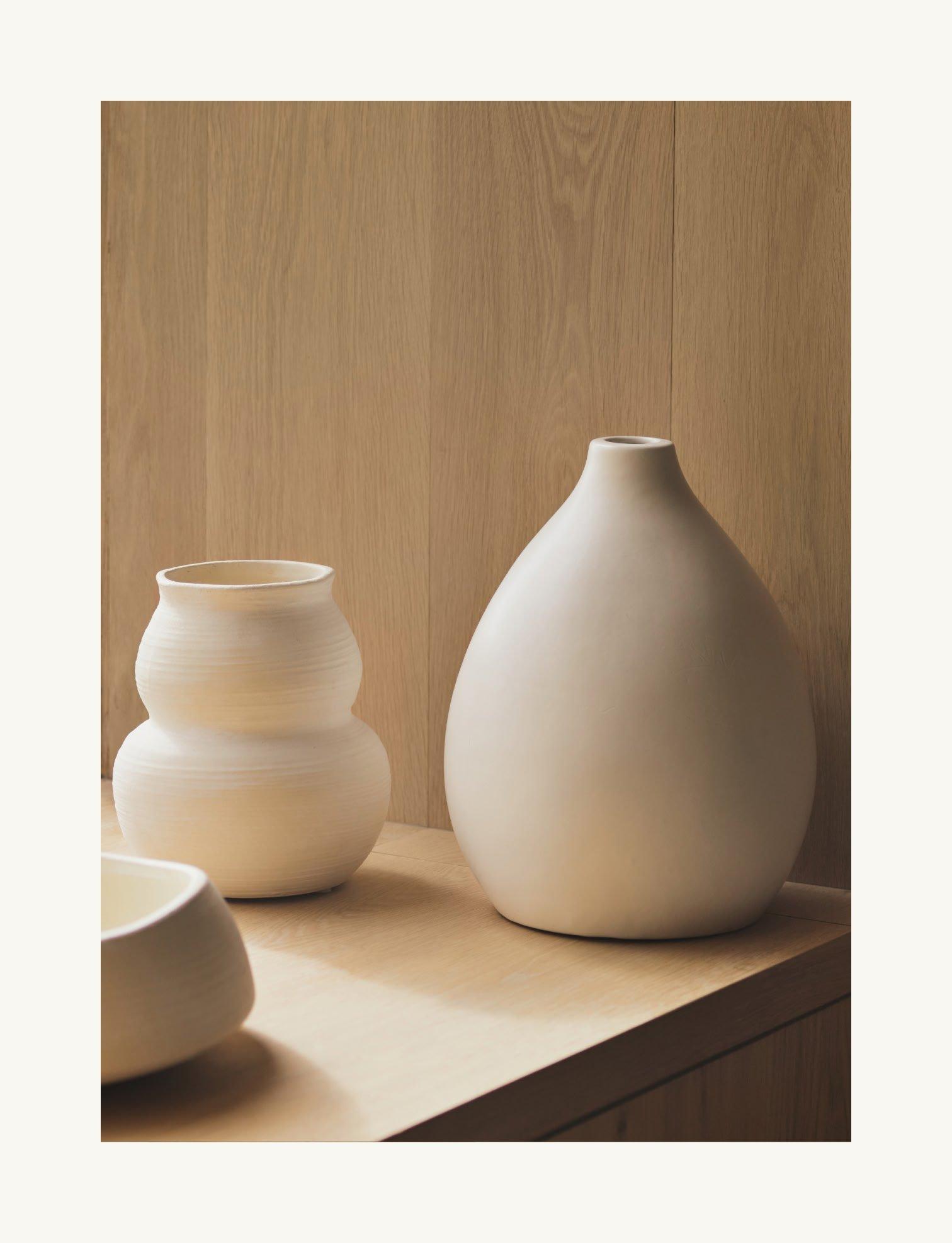 a couple of white vases sitting on a wooden table