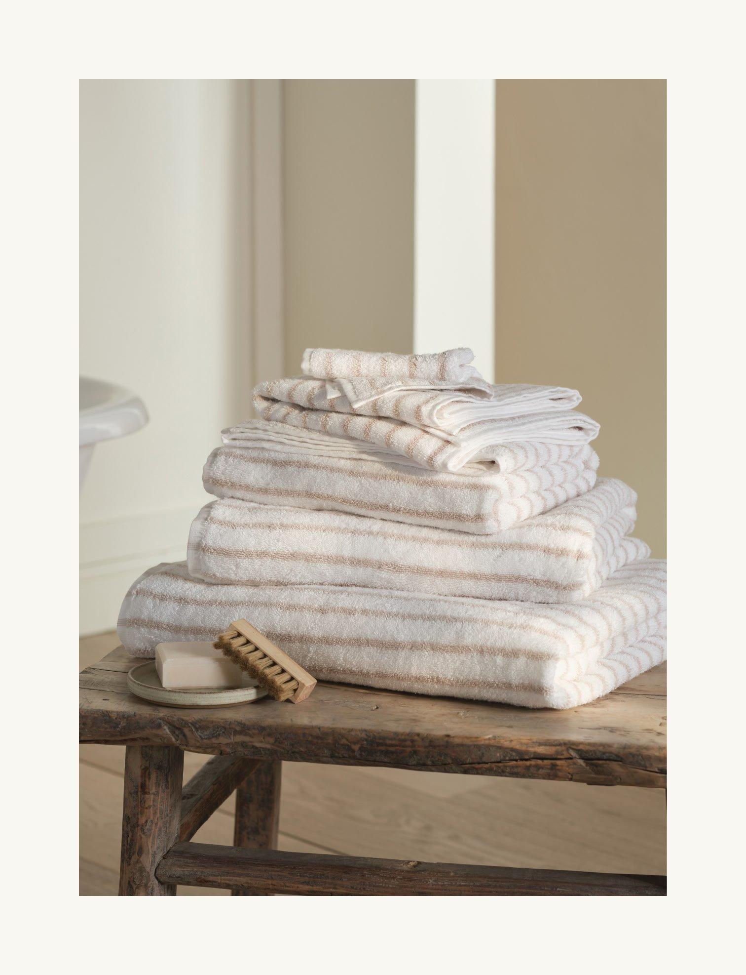 a stack of towels on a wooden table with a soap dish