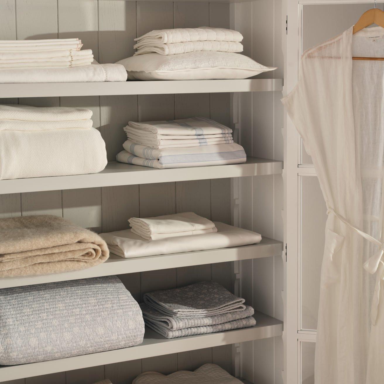 a closet with a robe and towels on shelves