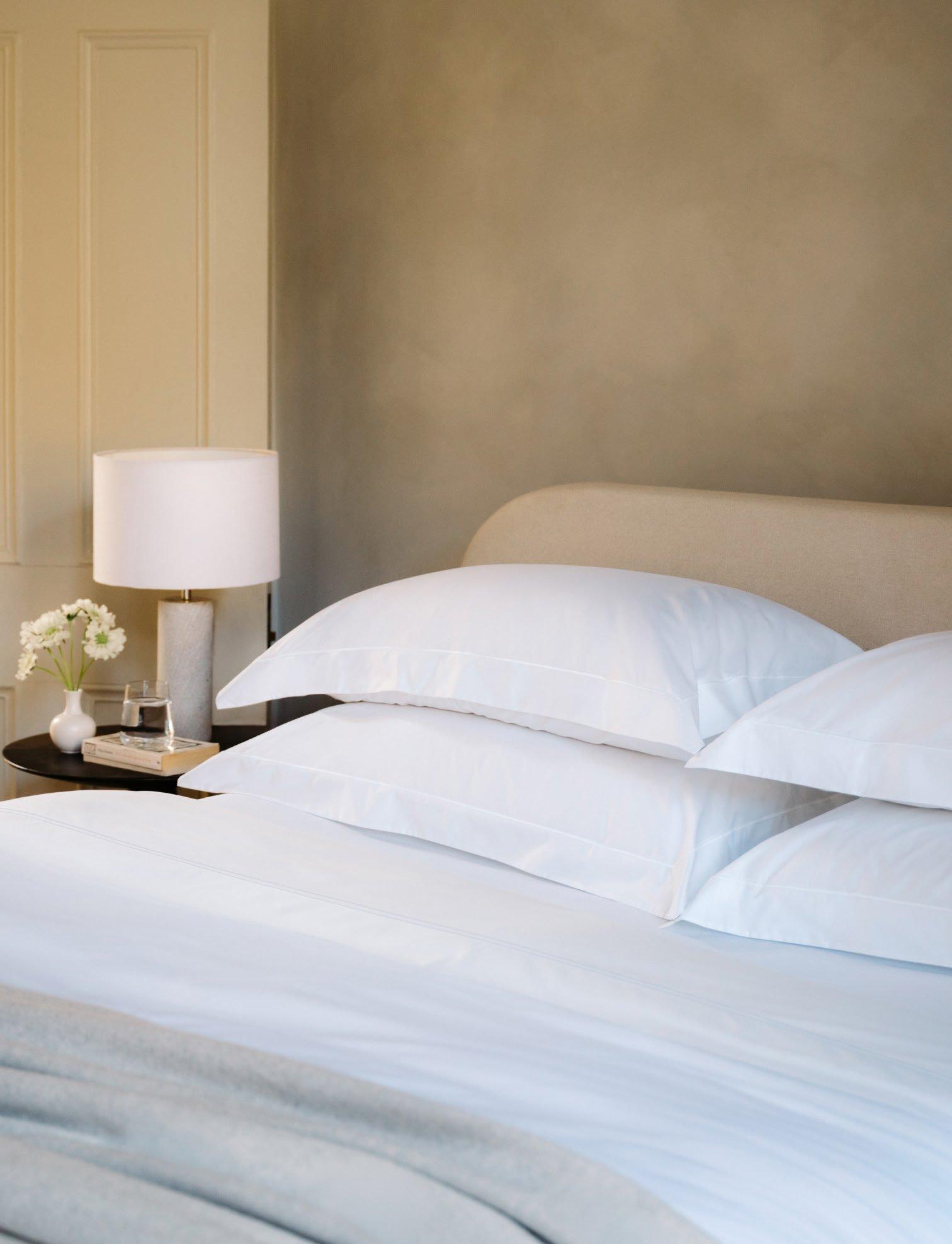 a bed with four pillows and a lamp on the night stand