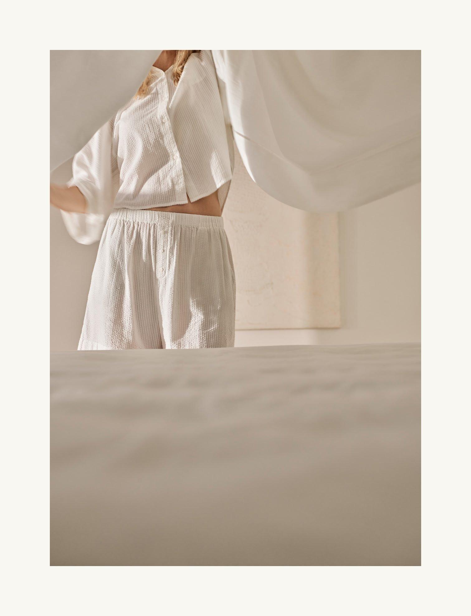 a woman standing in a white room with a sheet over her