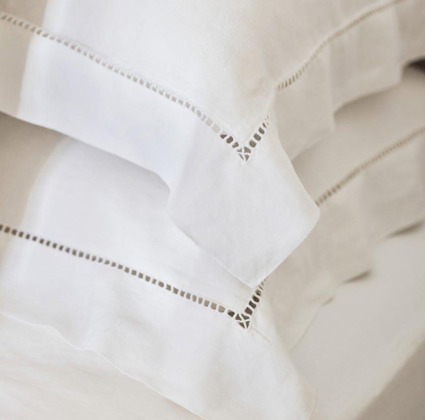 a close up of a bed with white sheets and pillows