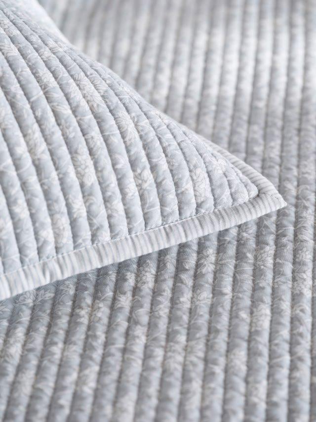 a close up of a bed with a quilt and pillows