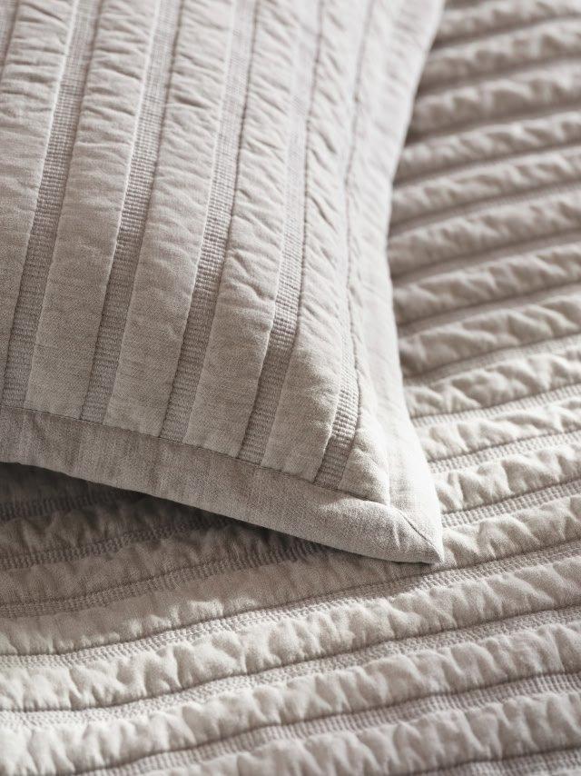 a close up of a bed with a quilt and pillows
