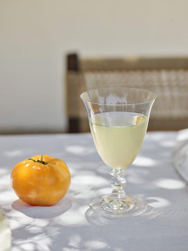 a glass of wine and a tomato on a table