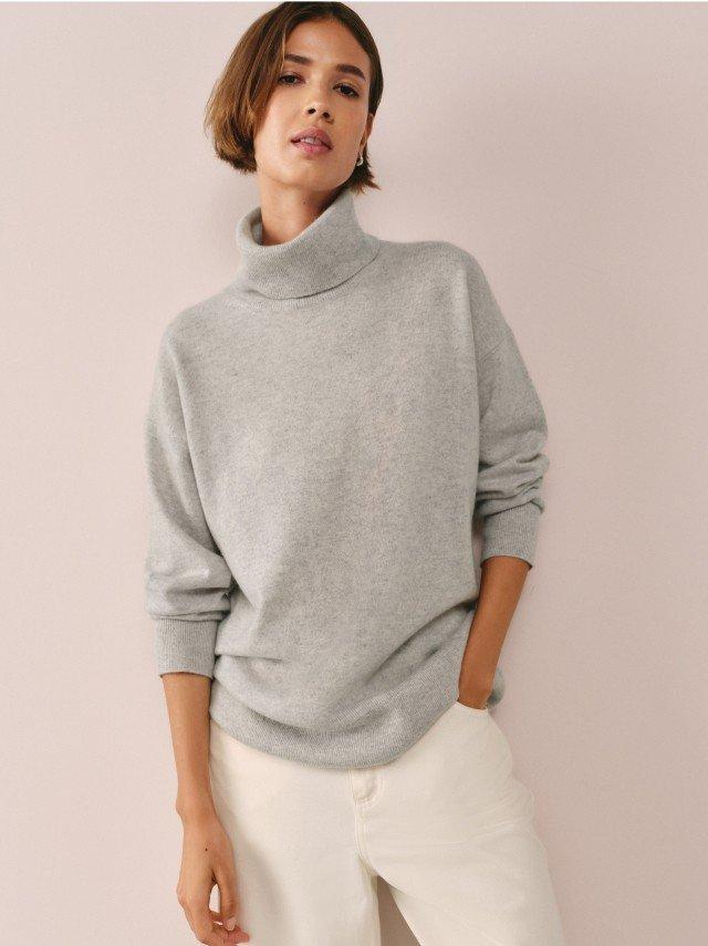 a woman in a grey sweater with a yellow circle on it