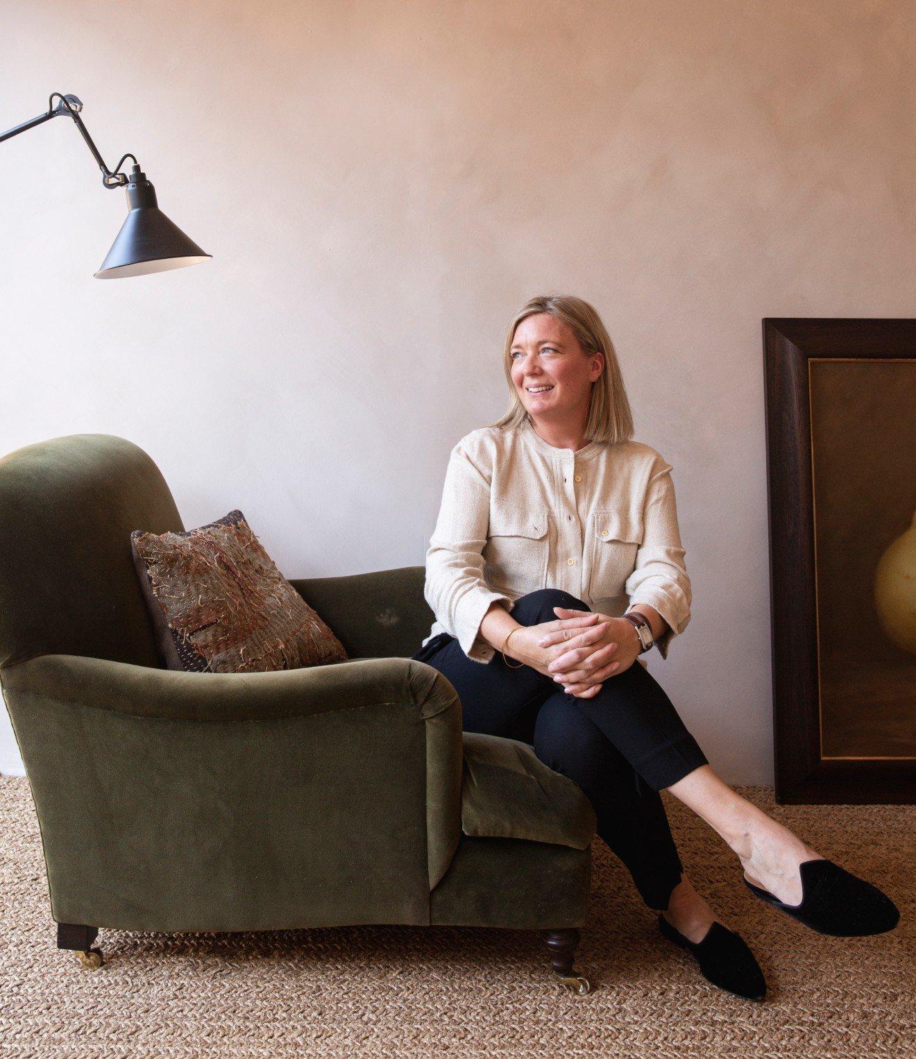 a woman sitting on a chair in a living room next to a painting