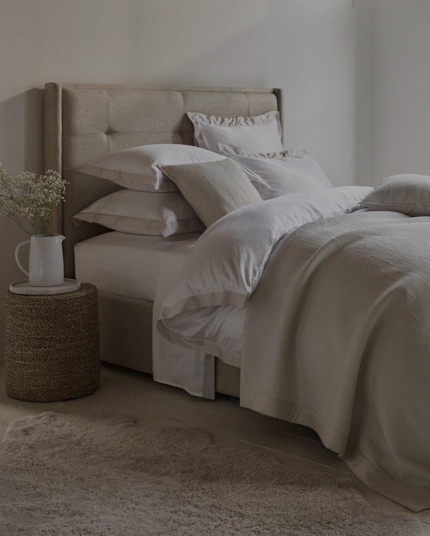 a bed with a white comforter and pillows in a bedroom