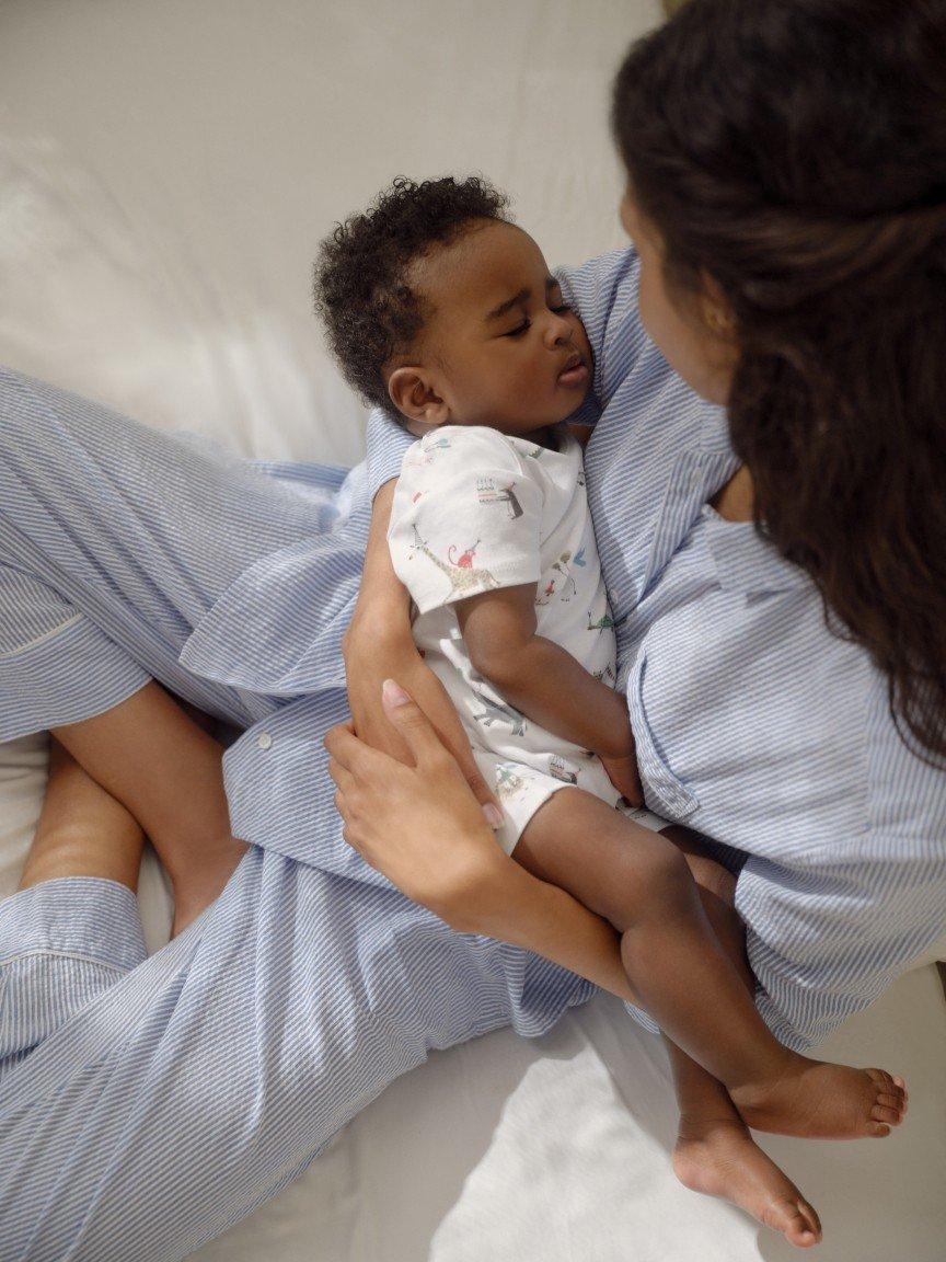 a woman in pajamas holding a baby in her lap