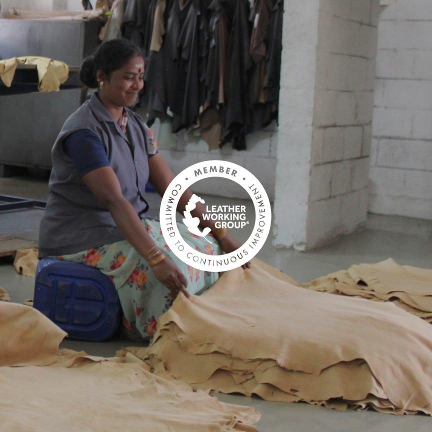 a woman sitting on floor in a factory cutting up leather