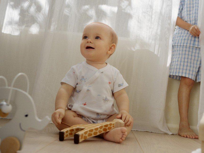 a baby sitting on the floor next to a window