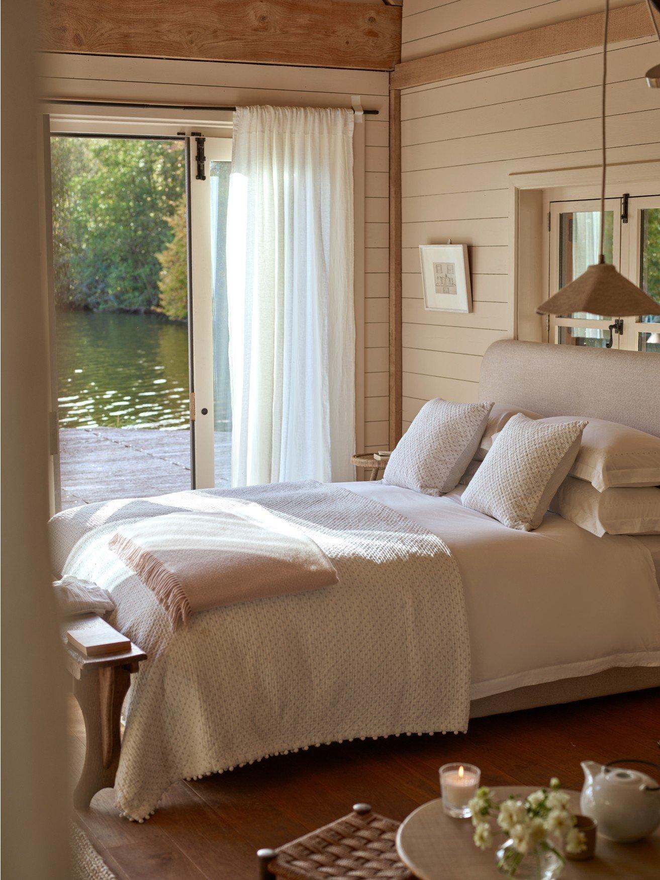 a bedroom with a bed, a table, a chair and a lamp