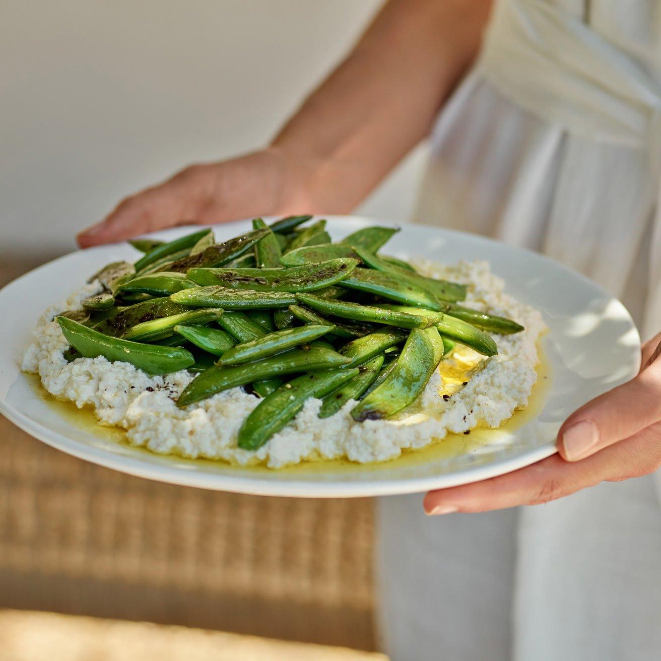 a person holding a plate of food with green beans on it