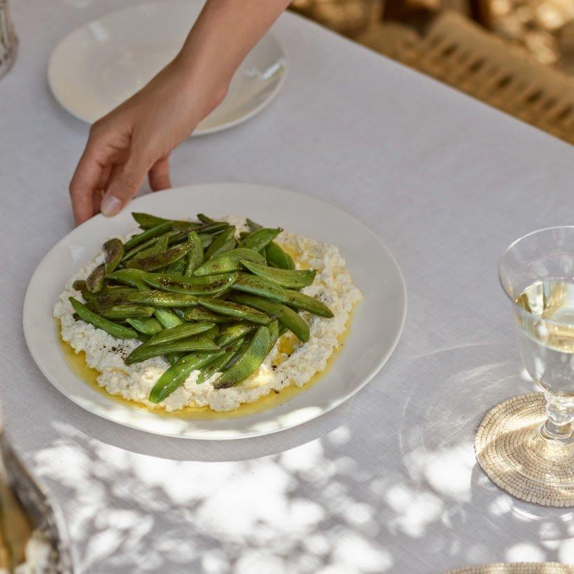 a person is holding a plate of food with green beans on it