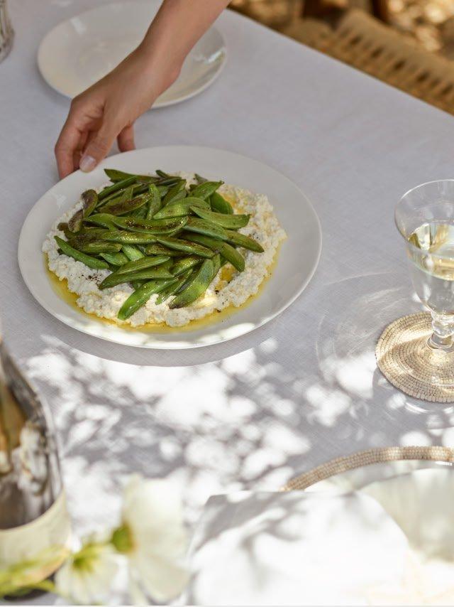 a person is holding a plate of food with green beans on it