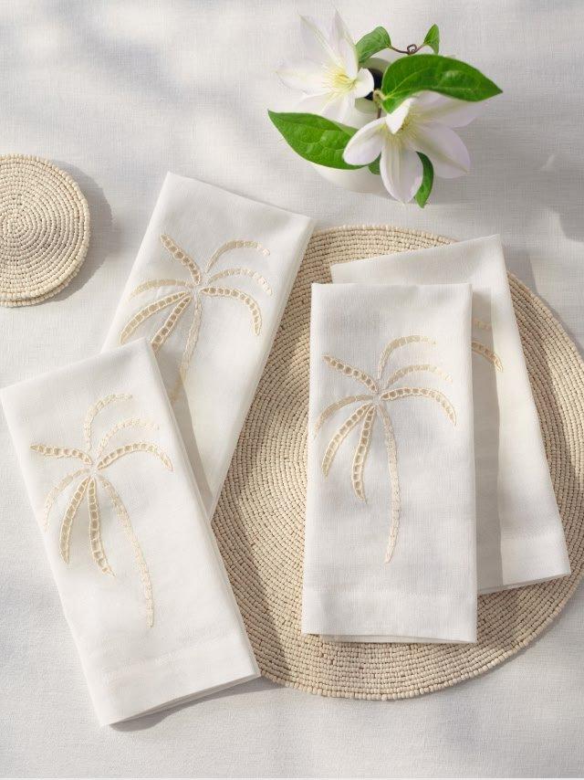 a table setting with four white napkins and a white flower