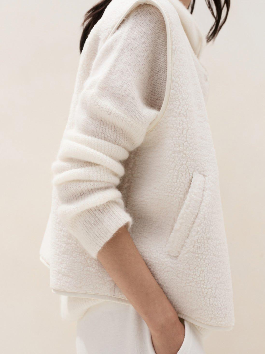 a woman in white sweater and pants standing up