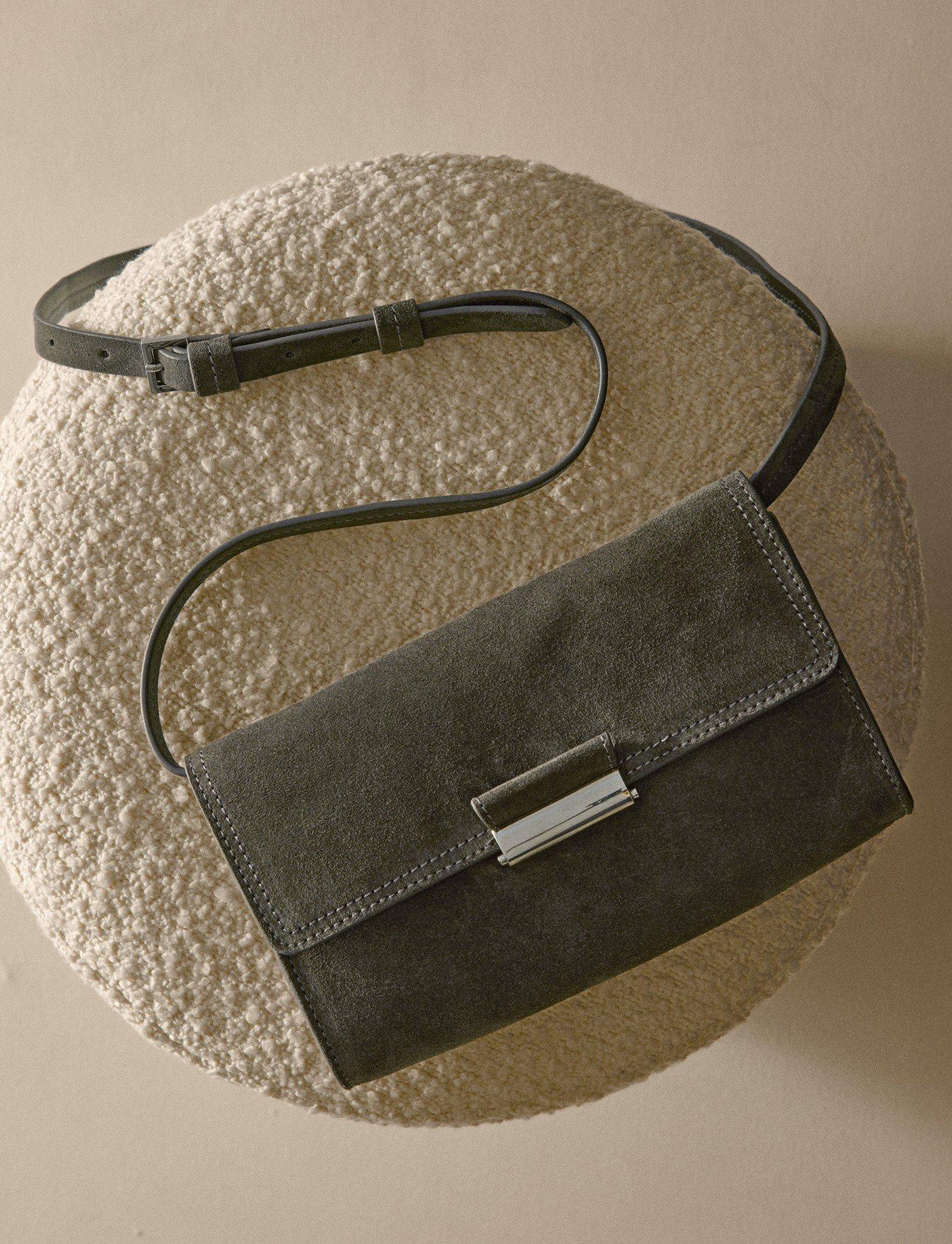 a purse on a round pillow with a strap hanging down