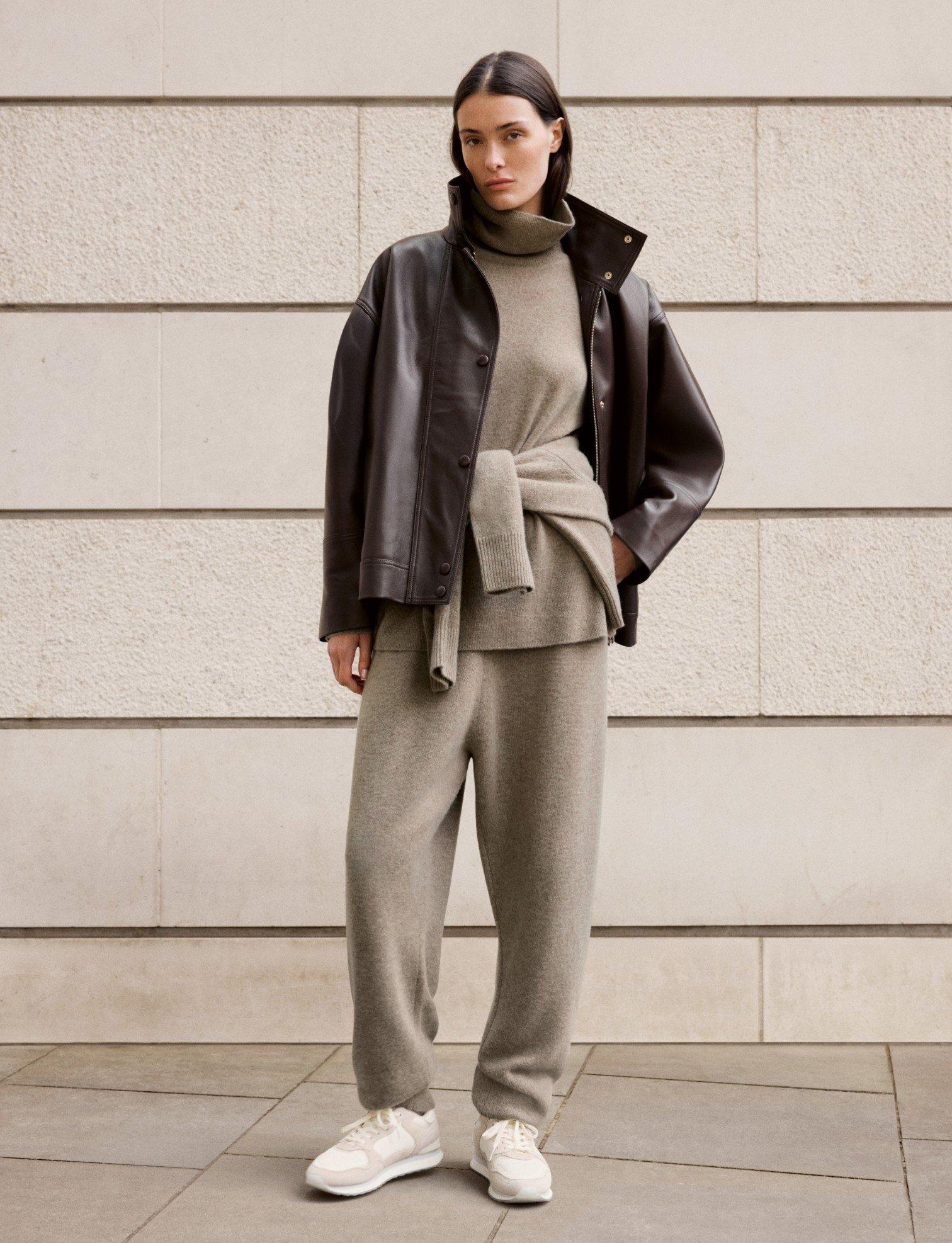 a woman in a beige jacket and pants standing outside