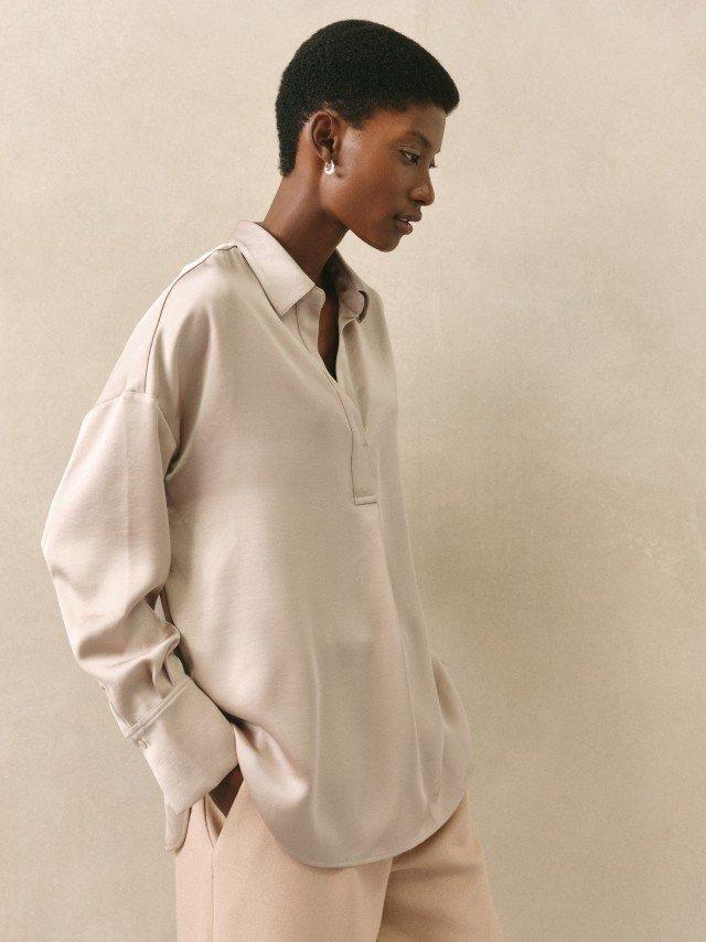 a woman in a beige shirt and tan pants standing