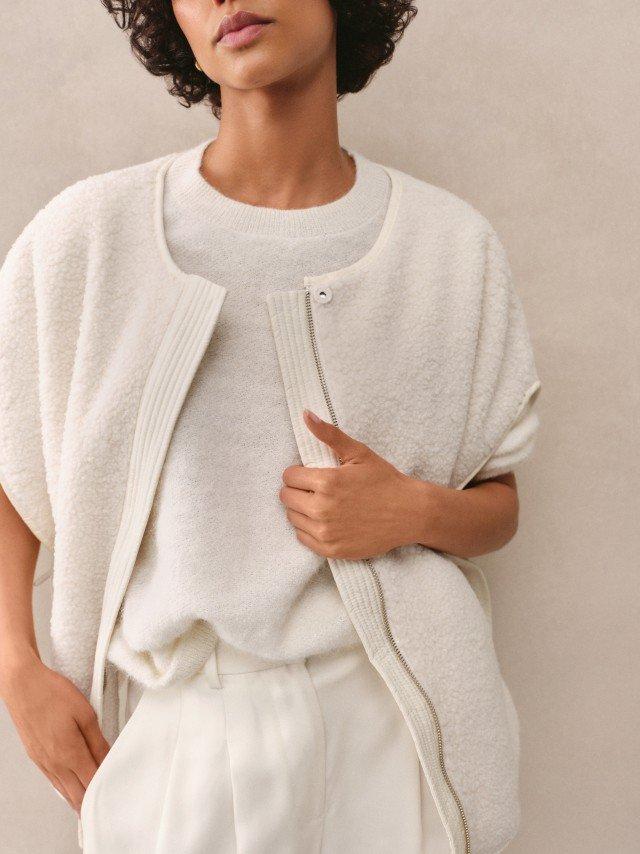 a woman in white pants and a white sweater standing up